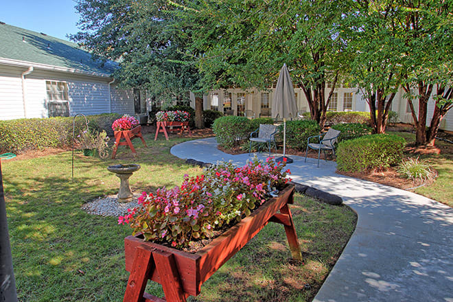 A serene garden with vibrant flowers, a winding pathway, and cozy patio seating.