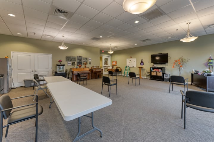 A spacious community room with chairs, tables, and a television set up for gatherings or meetings.