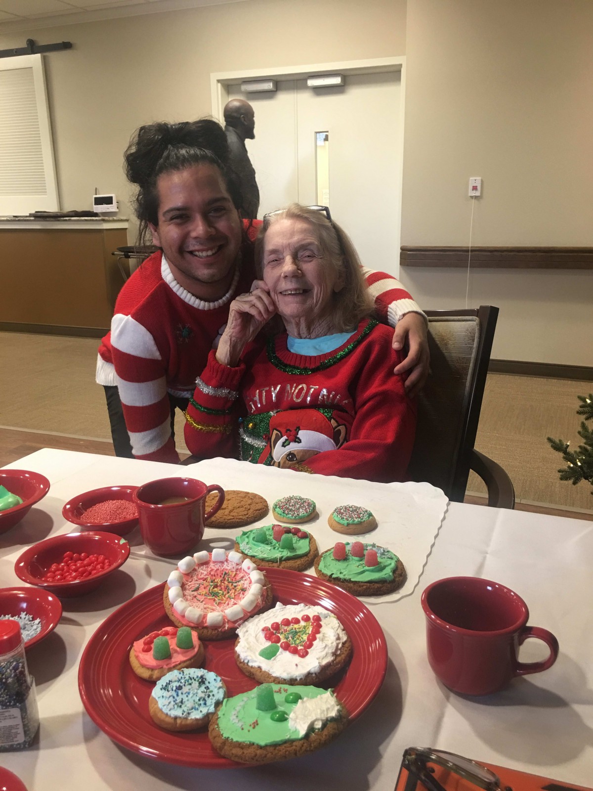 Two people enjoying a festive holiday gathering with decorated cookies on the table.