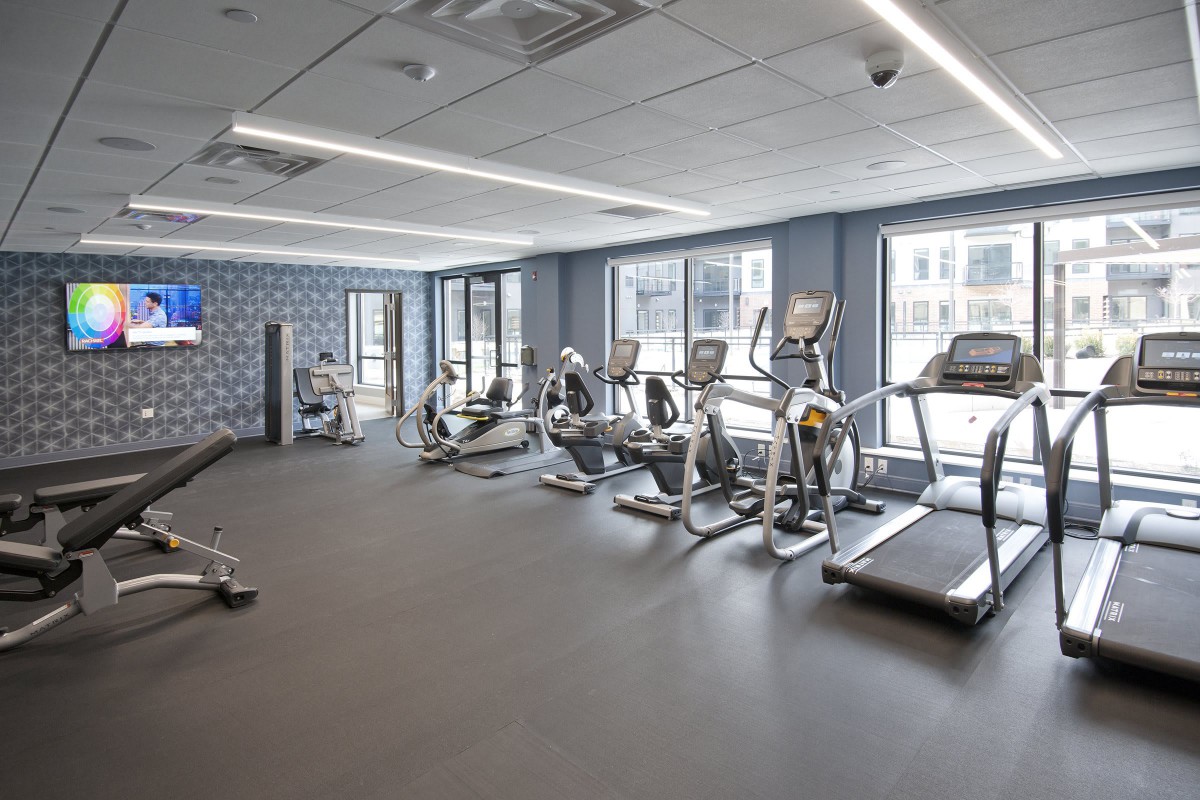 A modern gym with various cardio equipment, including treadmills and stationary bikes.