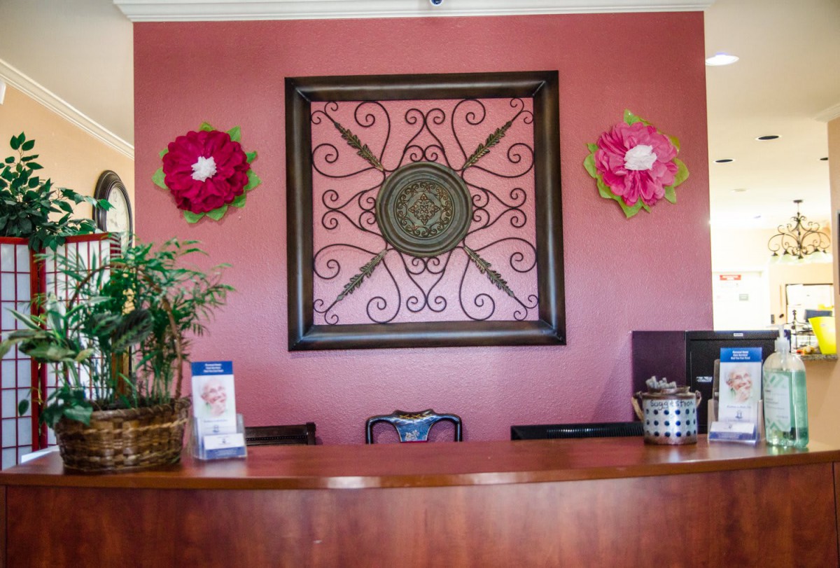 A reception area with a decorative wall piece and flower arrangements.