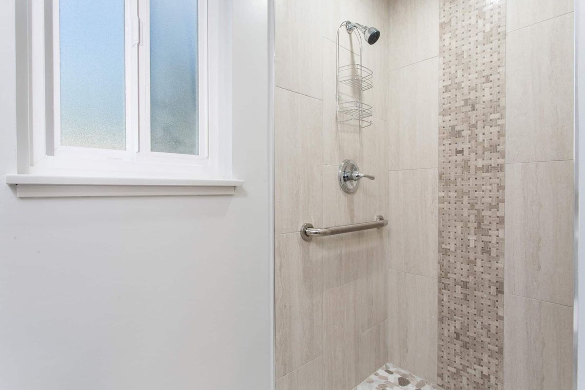 A modern bathroom with a tiled shower and a window.