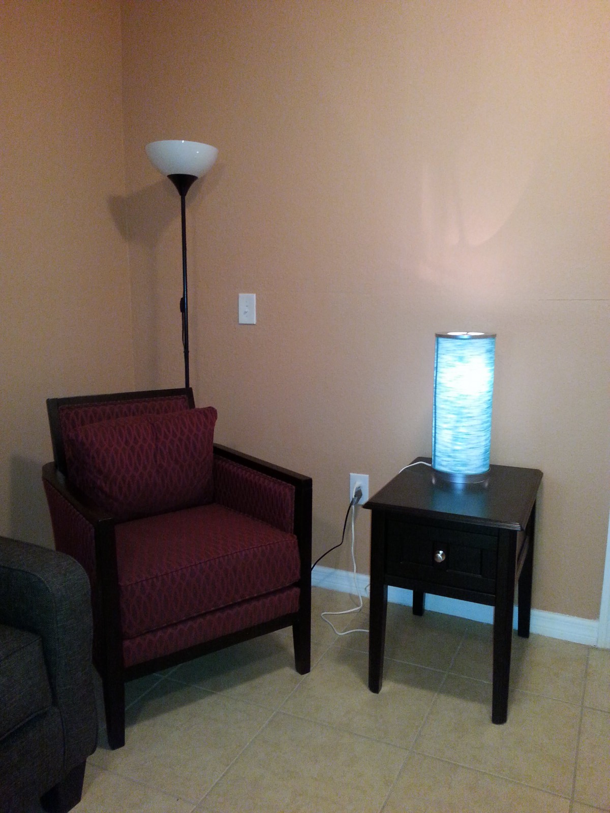 A cozy corner featuring a comfortable chair, a side table with a glowing lamp, and a floor lamp.