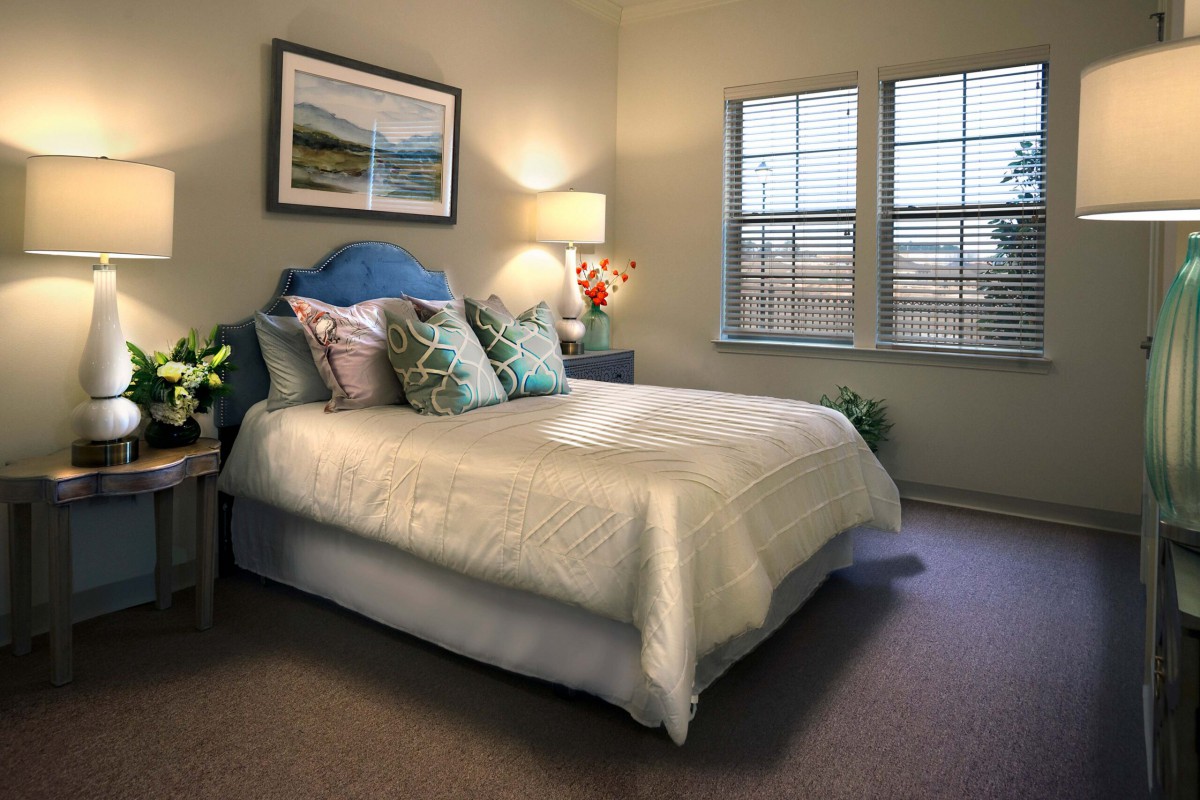 A cozy bedroom with a well-decorated bed, soft lighting, and natural light coming through the window.