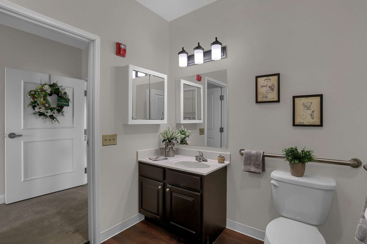 A modern bathroom with a vanity, mirror, and stylish light fixture.
