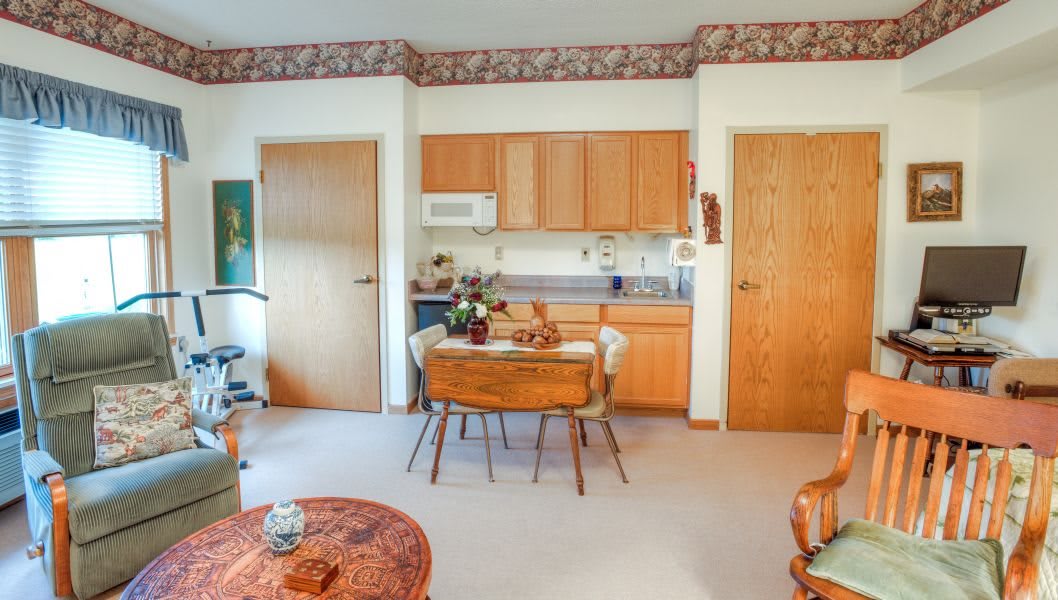 A cozy kitchen and dining area with wooden cabinets and a small table set for two.