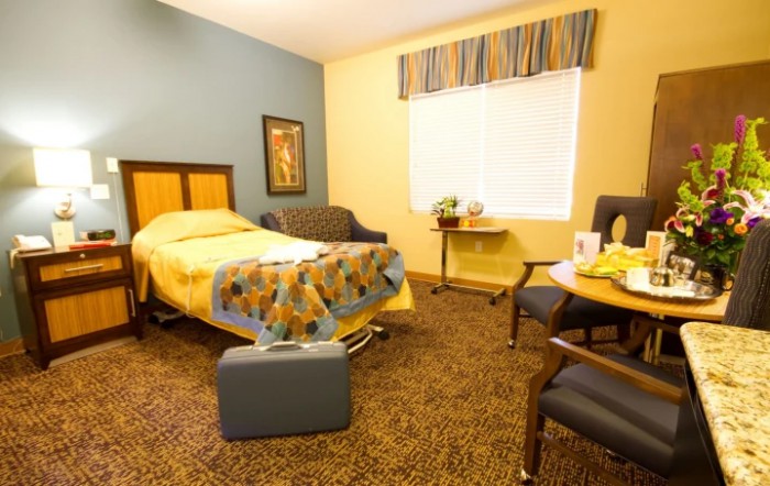 A neatly organized bedroom with a bed, chairs, and a window.