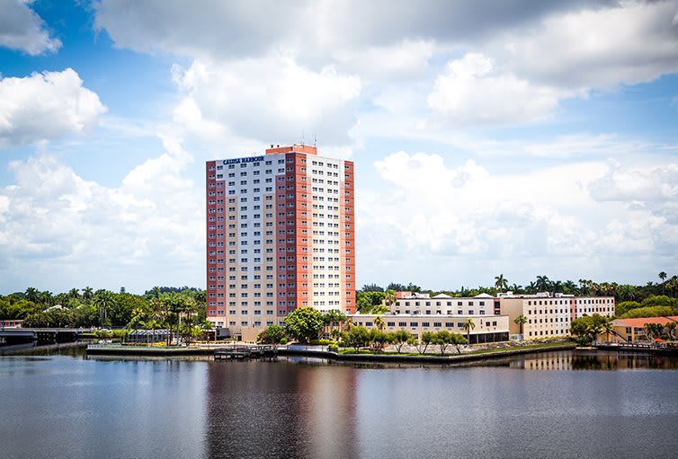 A high-rise building overlooking a river on a cloudy day.