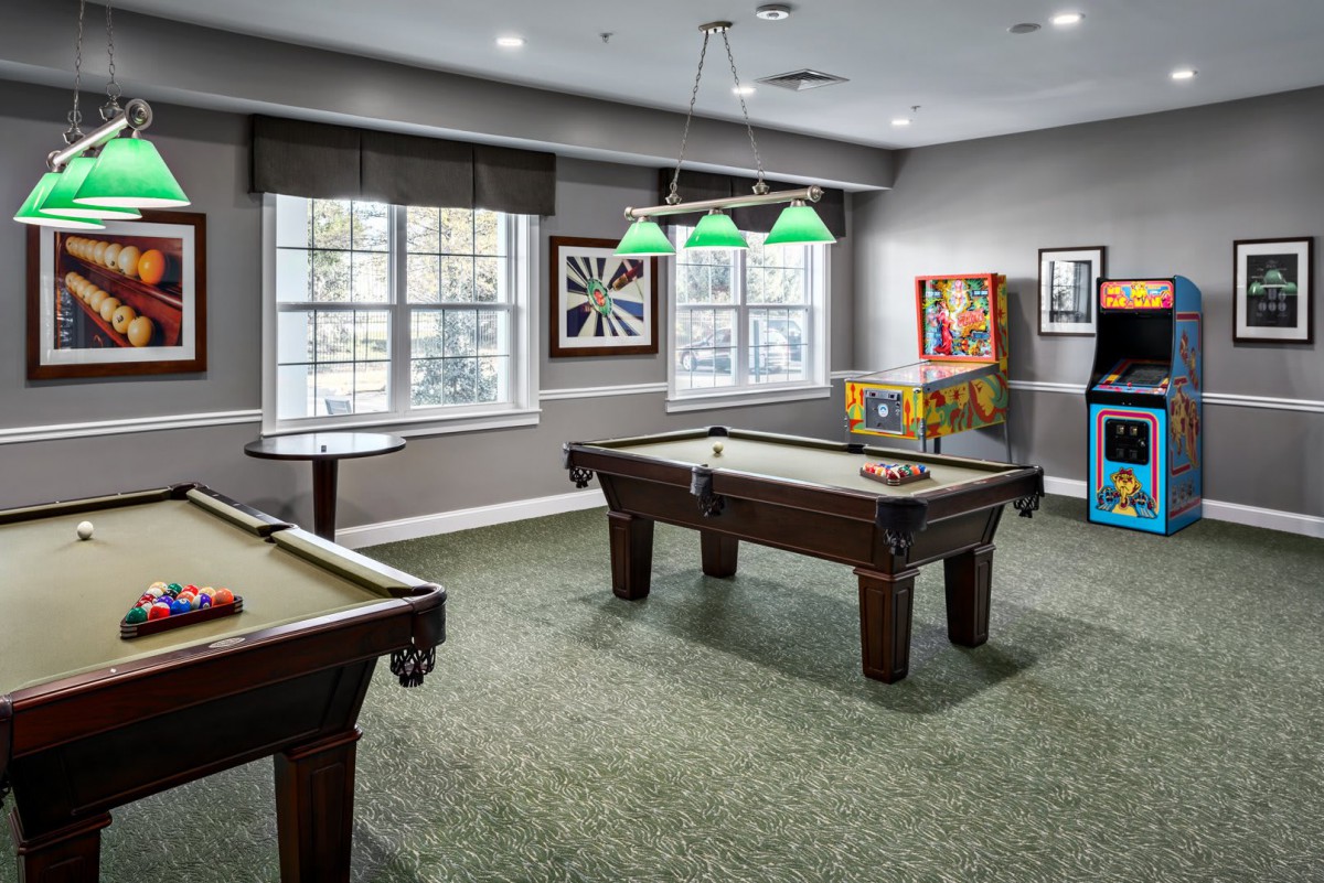A well-furnished game room featuring a pool table and arcade games.