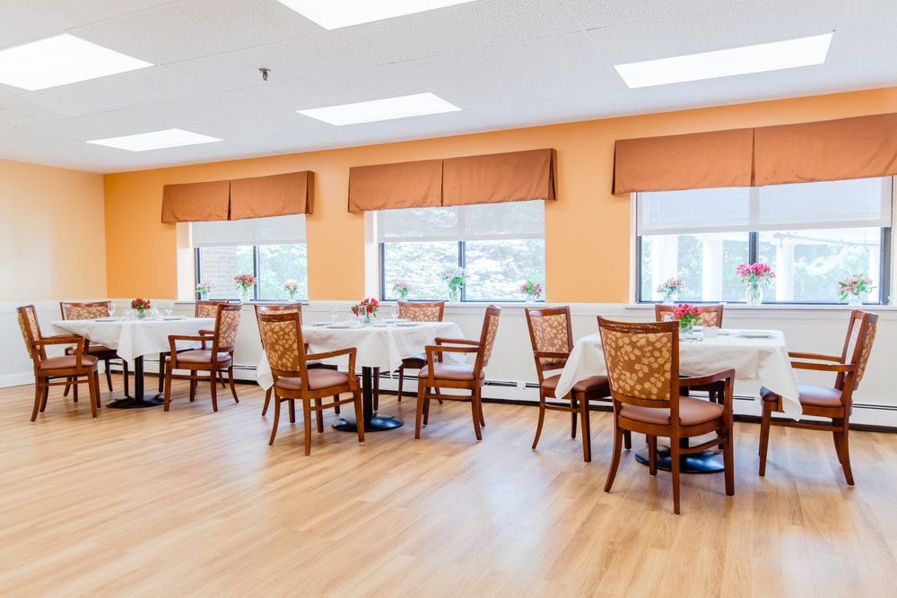 A bright and spacious dining room with neatly arranged tables and chairs.