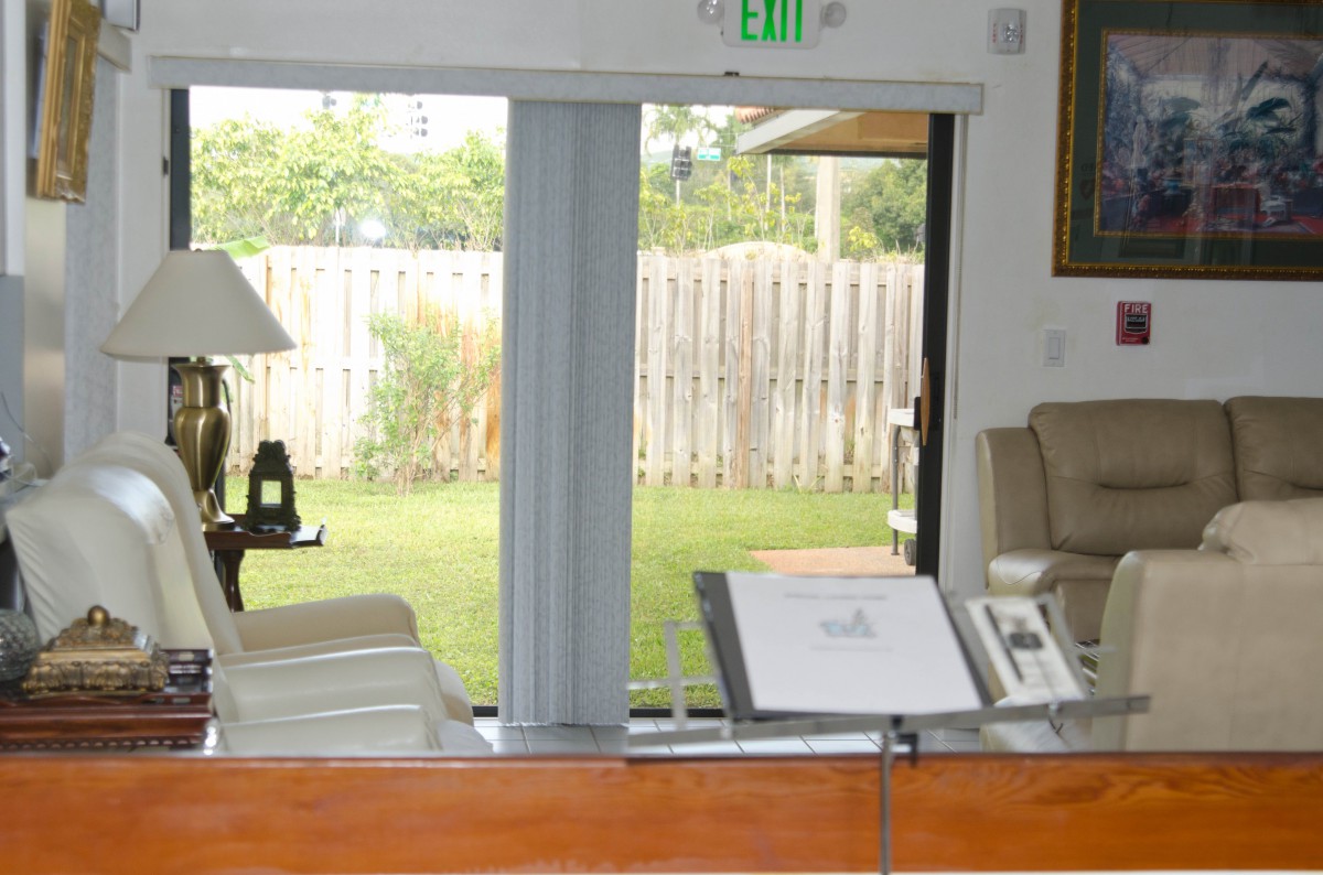 A cozy living room with a piano facing a sliding glass door leading to the backyard.