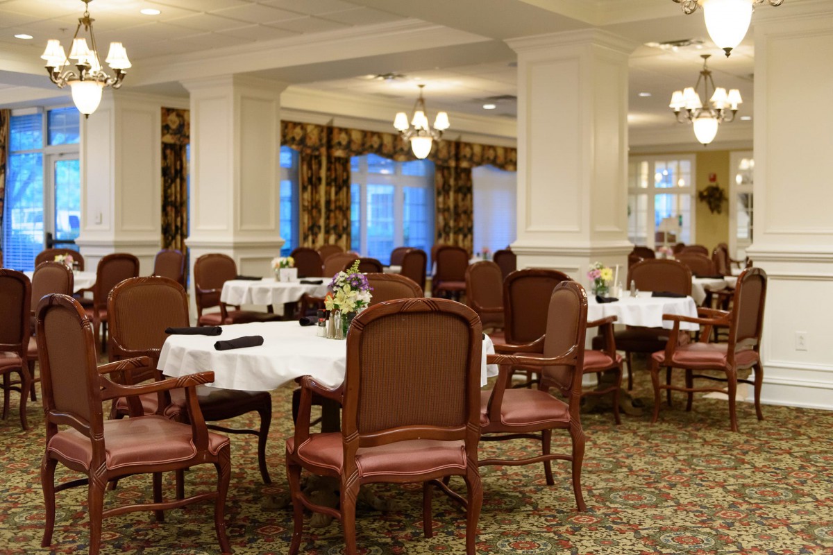 An elegant dining room with well-arranged tables and chairs, featuring classic decor and ambient lighting.
