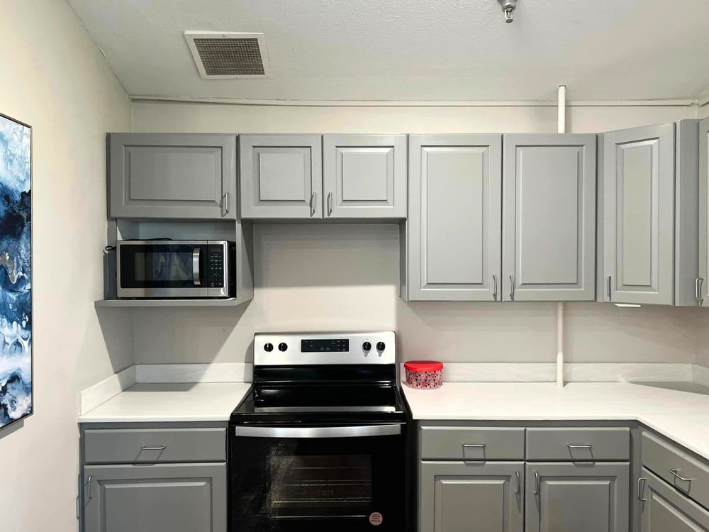A modern kitchen featuring gray cabinets, a microwave, and an electric stove.