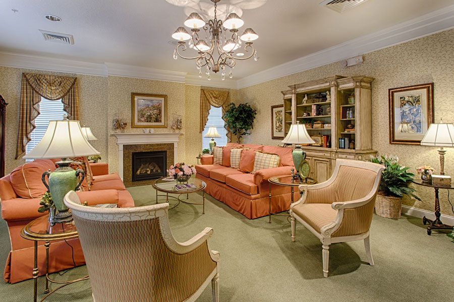 A cozy living room with elegant furniture, including a sofa and armchairs, centered around a fireplace and adorned with tasteful decor.