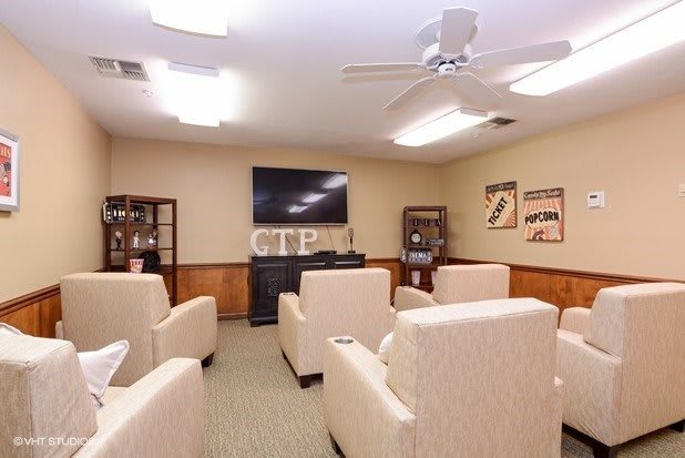 A cozy living room with comfortable armchairs, a television, and warm lighting.