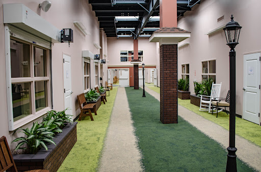 A serene indoor courtyard featuring a pathway lined with benches and greenery.