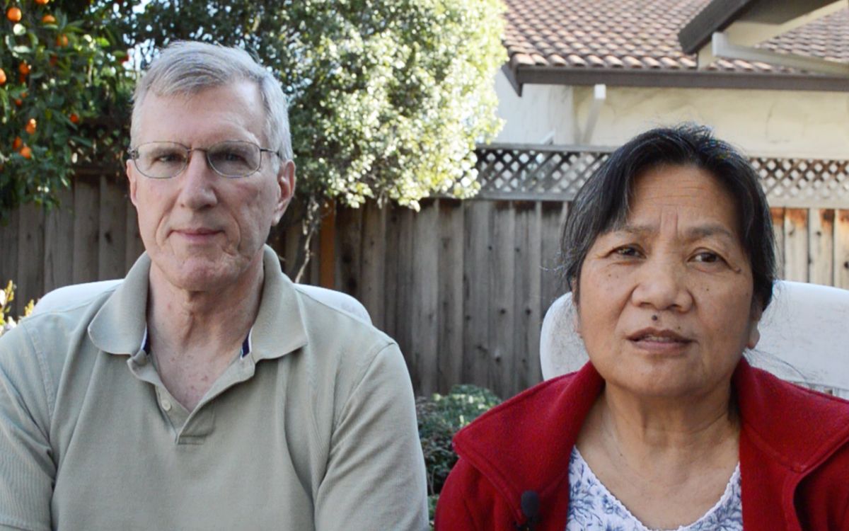 A couple sitting together in a garden on a sunny day.