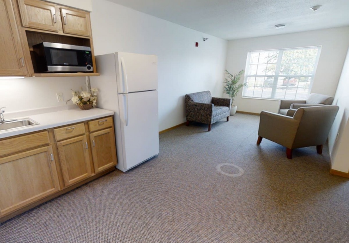 A cozy studio apartment with a kitchen and living area featuring modern furniture and bright natural lighting.
