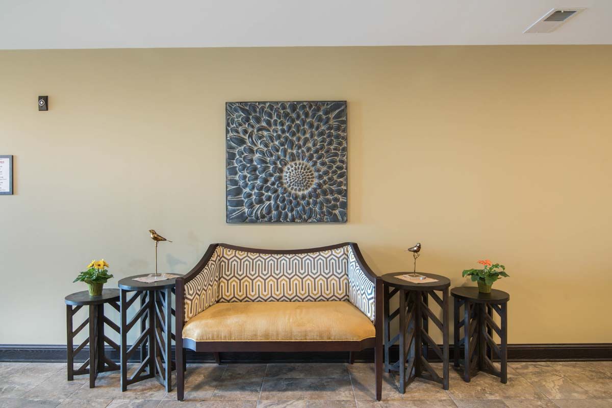 A stylish living room setup featuring a patterned sofa and two side tables, with decorative artwork adorning the wall.