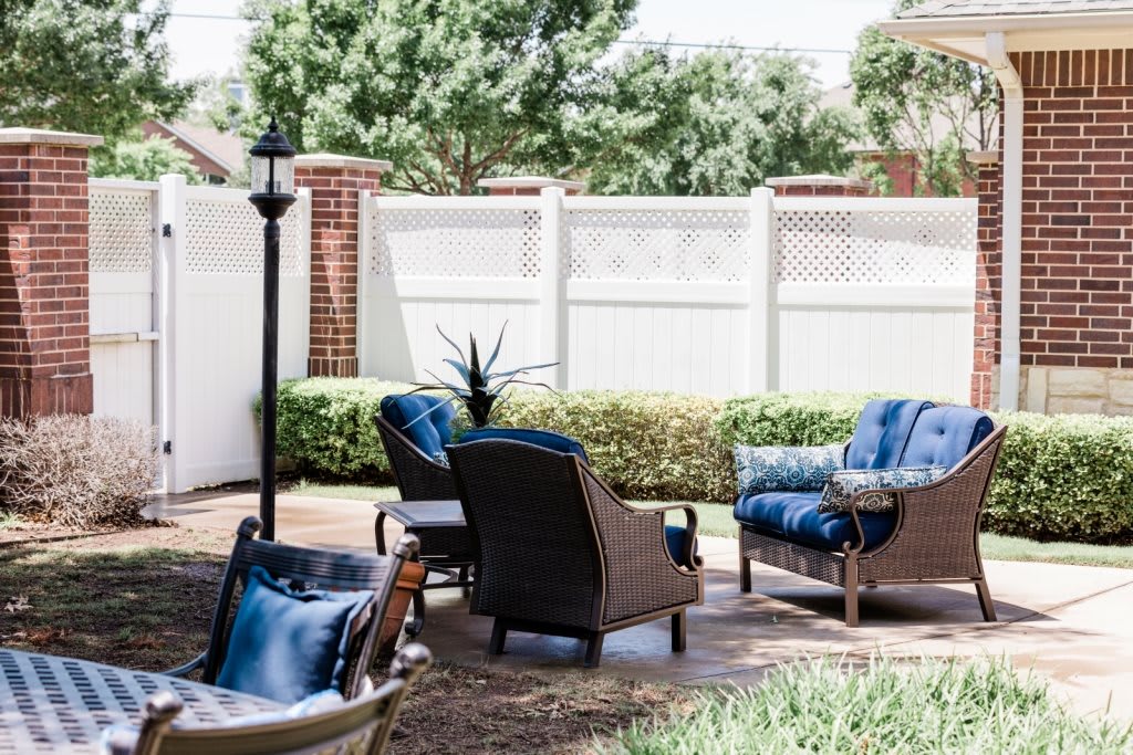 A cozy outdoor patio setup with chairs and a table, surrounded by greenery.