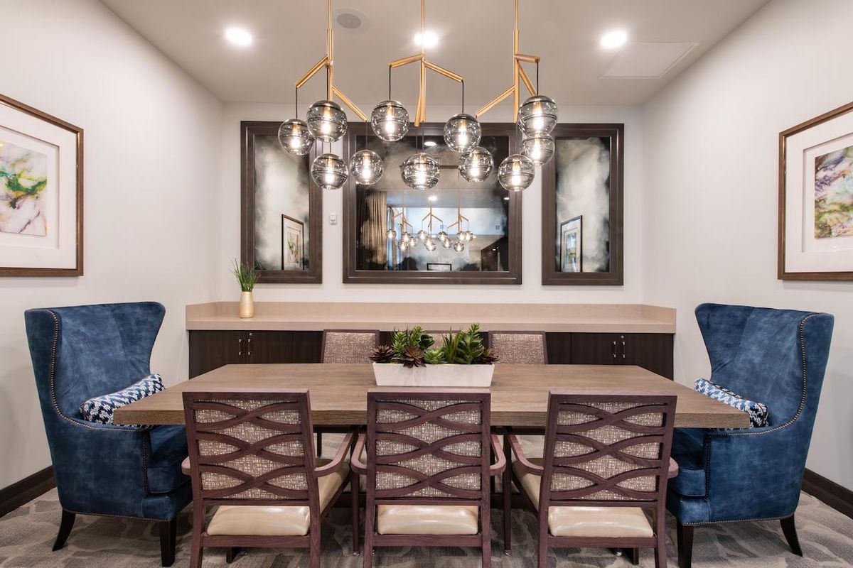 A contemporary dining room with a stylish chandelier and mirrored accents.