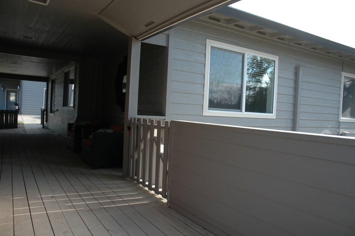 A view of a house's porch with a window and railing.