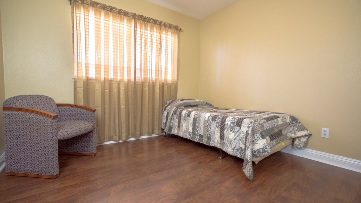 A minimalist bedroom with a single bed and wooden flooring.