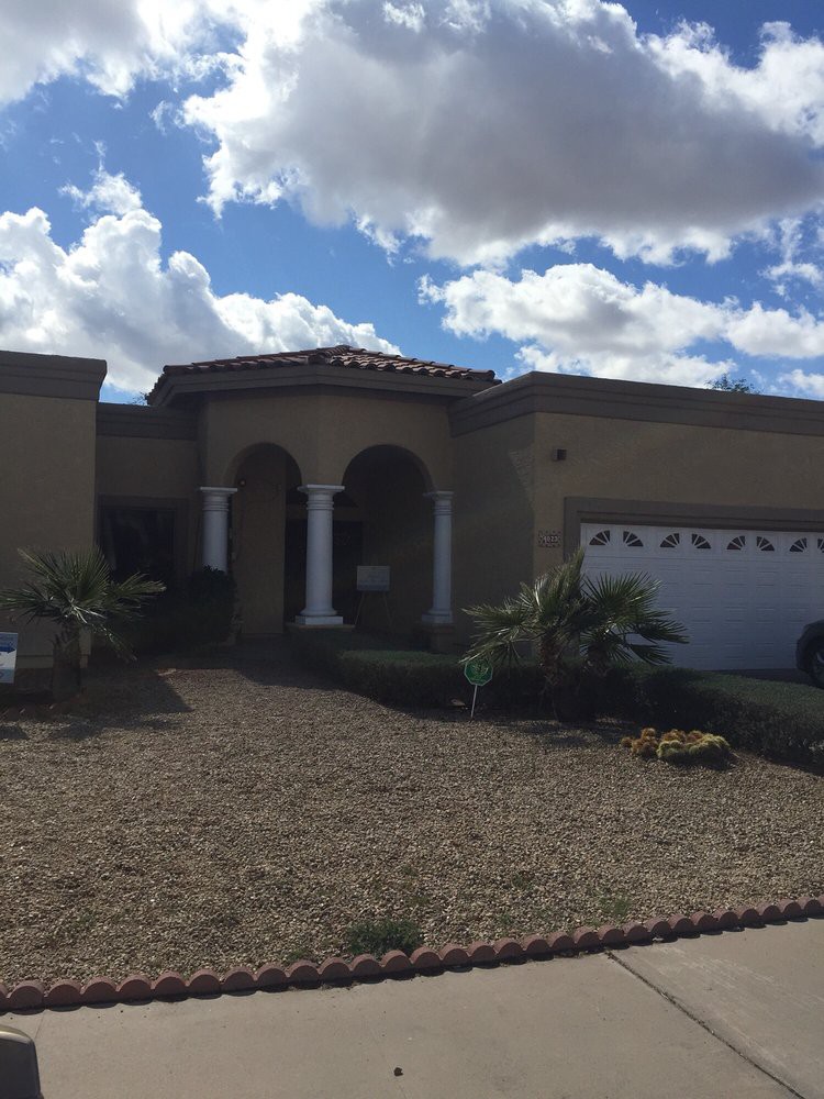 A suburban house with a garage and landscaped front yard under a cloudy sky.