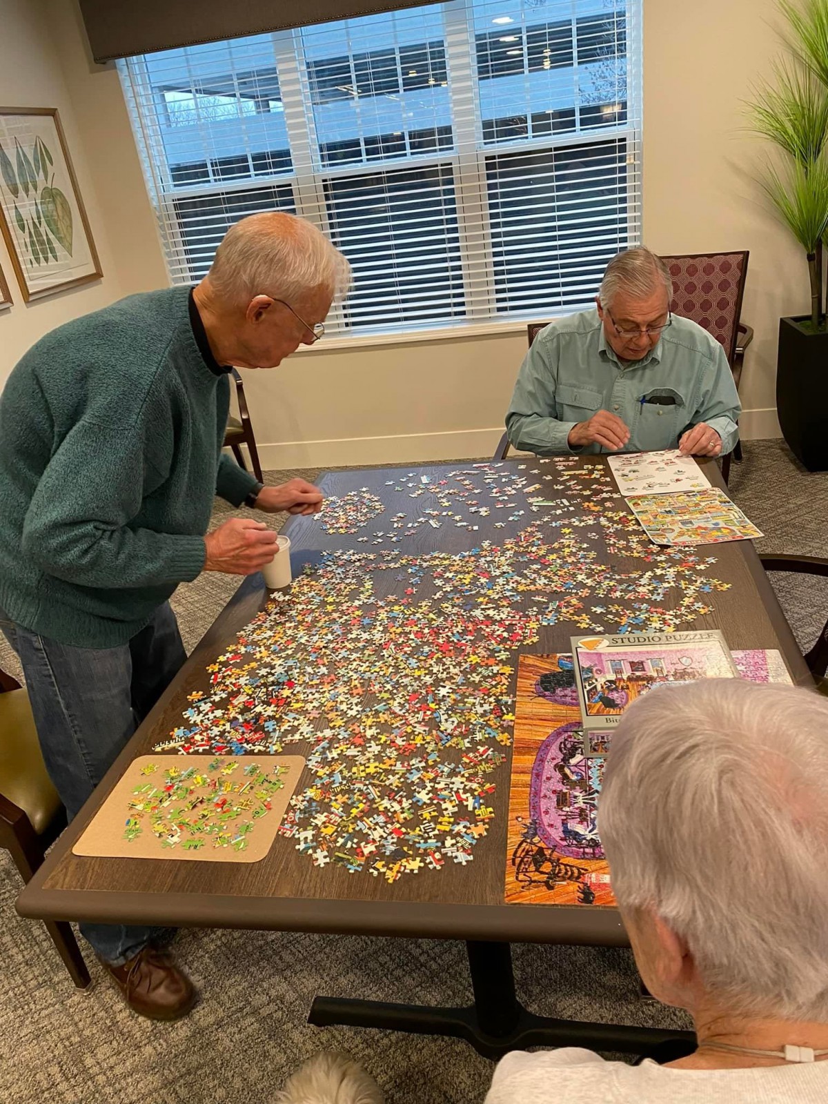 A group of seniors working together on a large puzzle at a table.