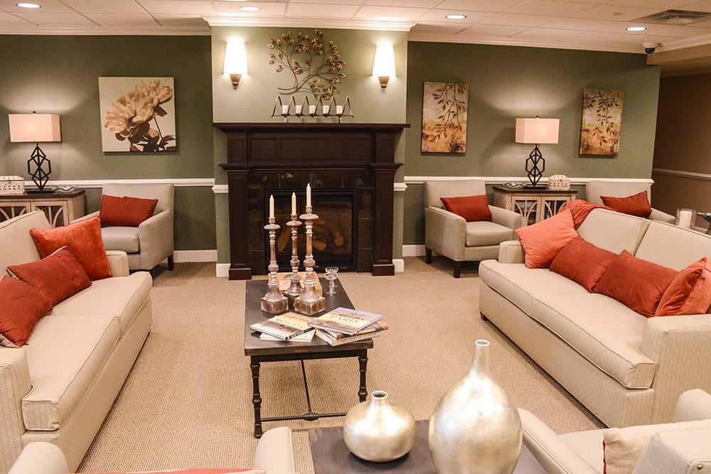 A cozy living room with neutral-toned sofas, a dark wooden fireplace, and decorative accents.