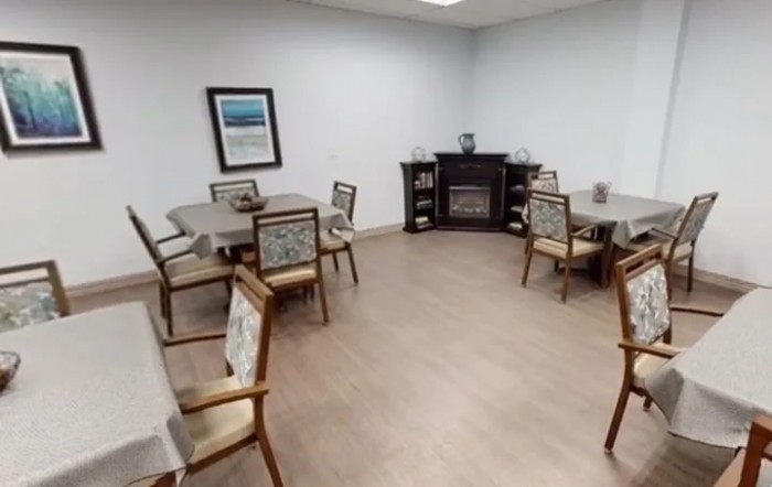 A cozy dining room setup with several tables and chairs, featuring a fireplace along the wall.