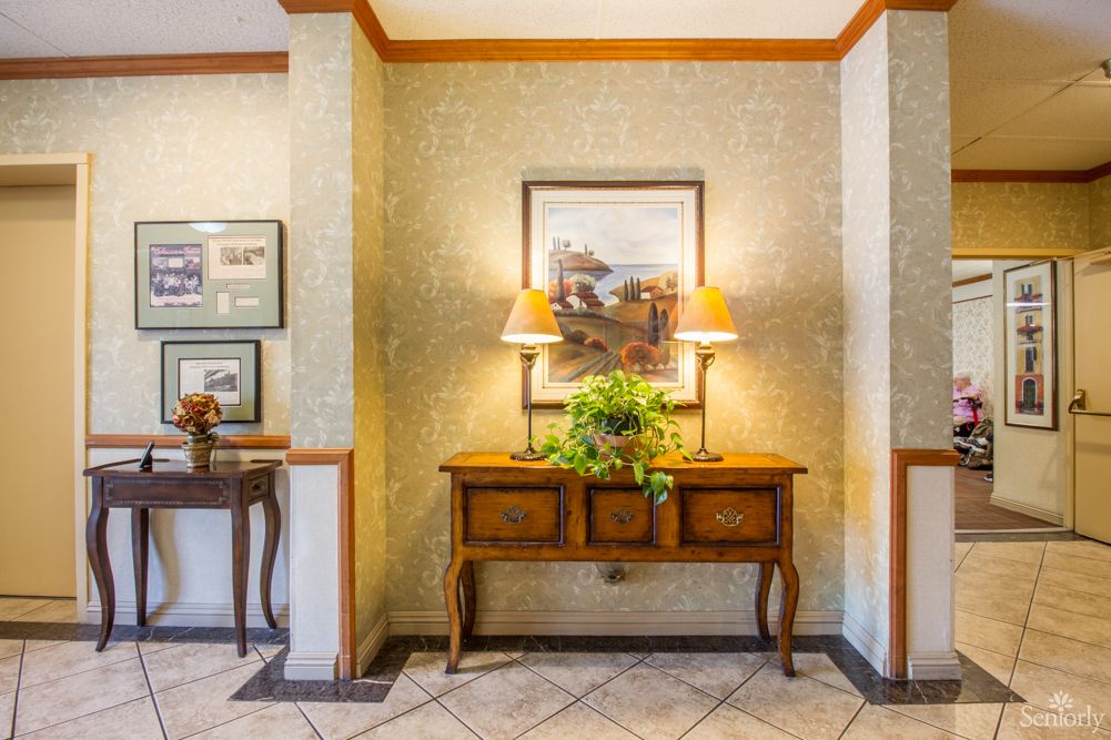 A warmly decorated hallway featuring a wooden table with lamps, artwork, and a plant.