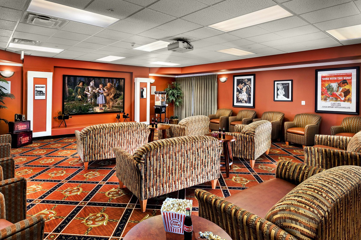 A modern lounge area with patterned sofas, a large TV screen, and artwork adorning the walls.