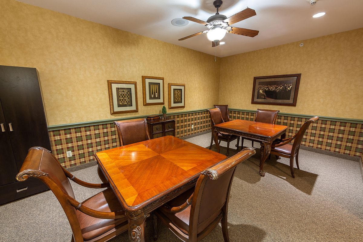 A cozy room with wooden tables and chairs, decorated with framed art and a ceiling fan.