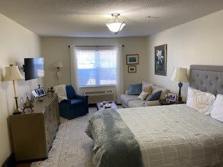 A cozy bedroom with a comfortable bed, seating area, and soft lighting.