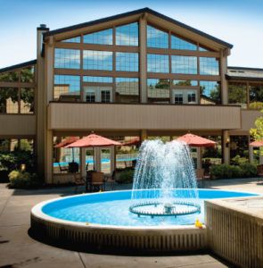 A hotel exterior with a central fountain and outdoor patio seating.