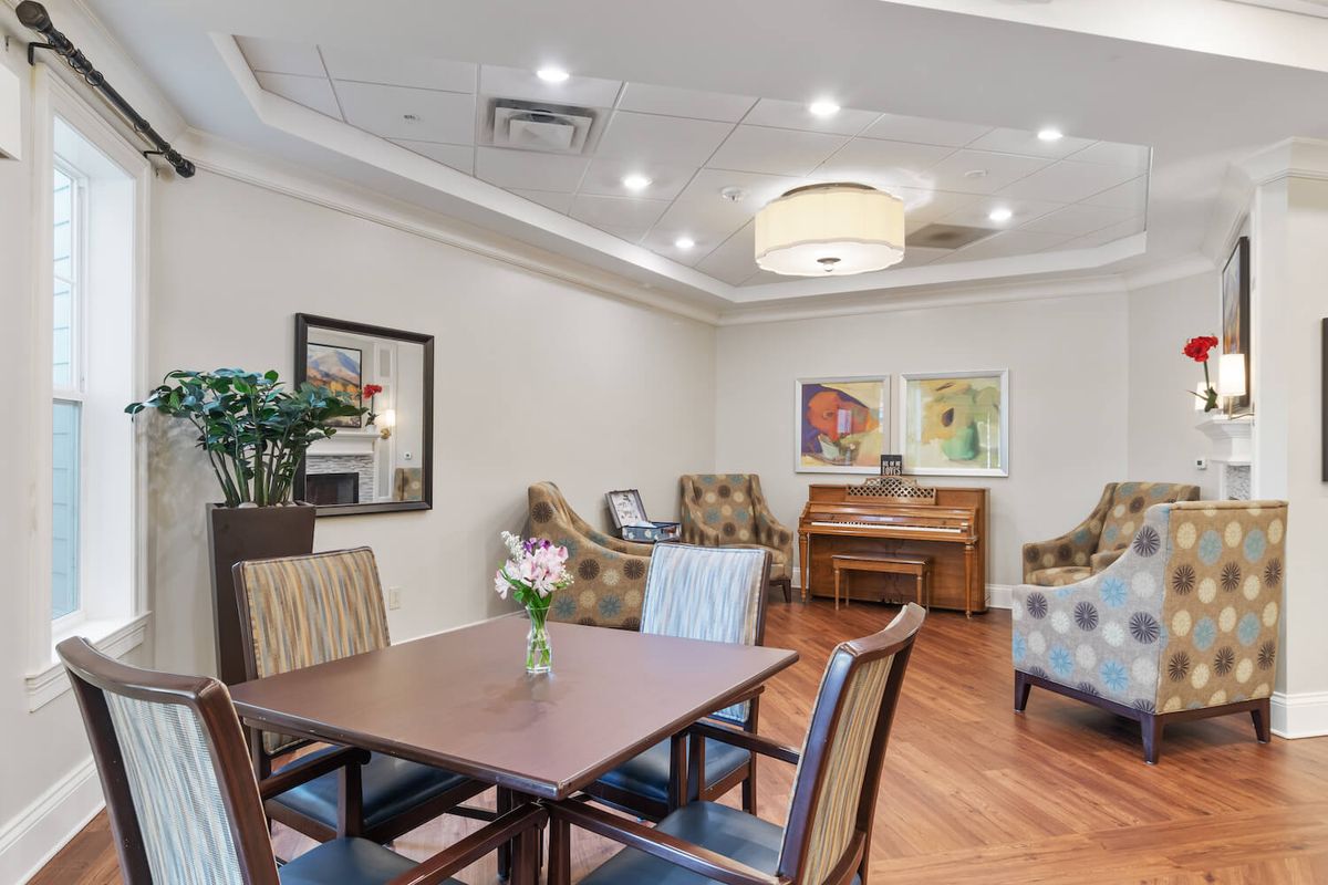 A cozy living room with comfortable seating, a piano, and decorative artwork.