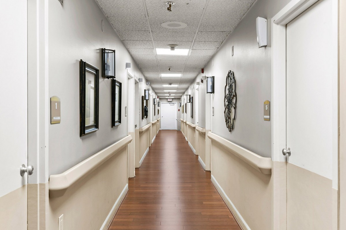 A clean and well-lit hospital corridor with framed pictures on the walls.