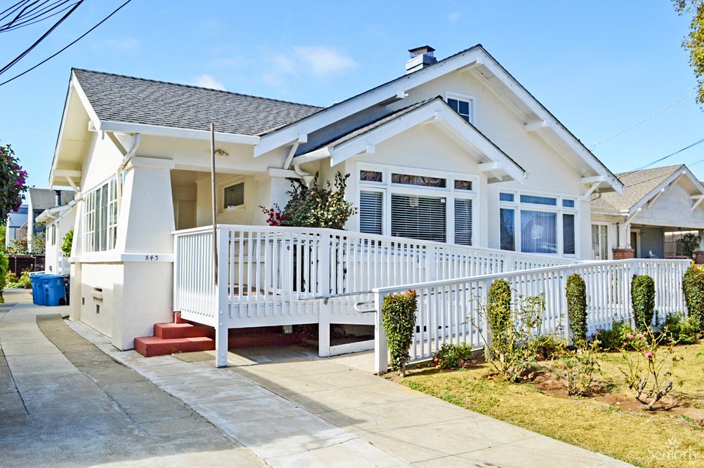 A charming white bungalow with a spacious porch and well-maintained landscaping.