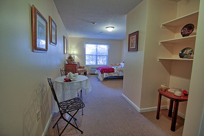 A cozy bedroom interior with a small table and chair, and neatly arranged decor.