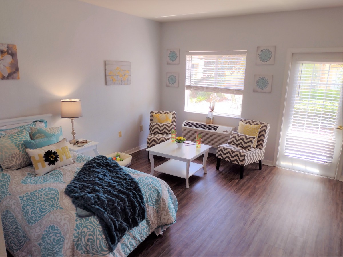 A cozy and modern bedroom interior with a bed, lamp, and seating area.