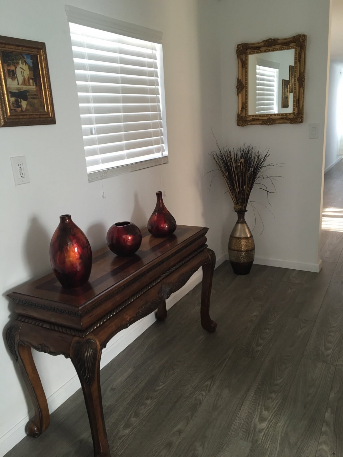 A well-decorated hallway with a wooden table adorned with vases, a mirror, and wall art.