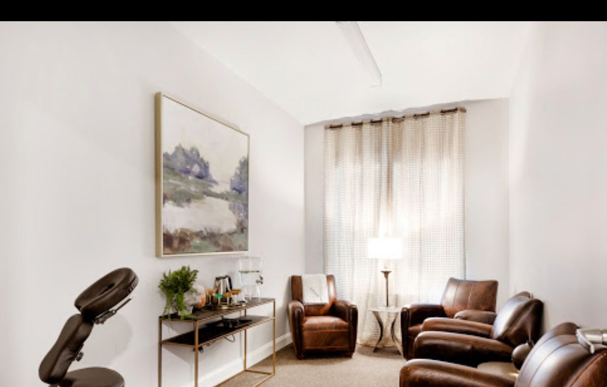 A cozy living room with leather chairs and a large painting on the wall.