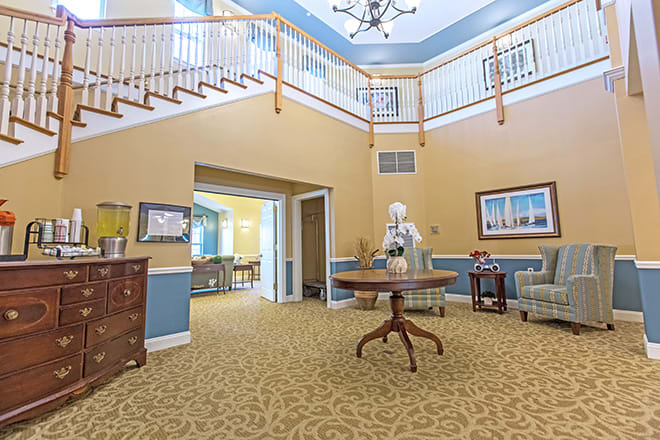 A brightly lit lobby with a central table and staircase.