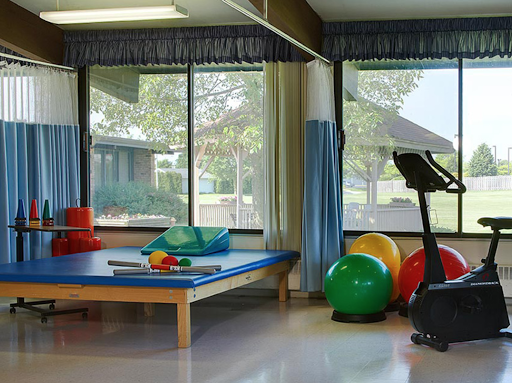 A bright and inviting therapy room featuring exercise equipment and colorful fitness balls.