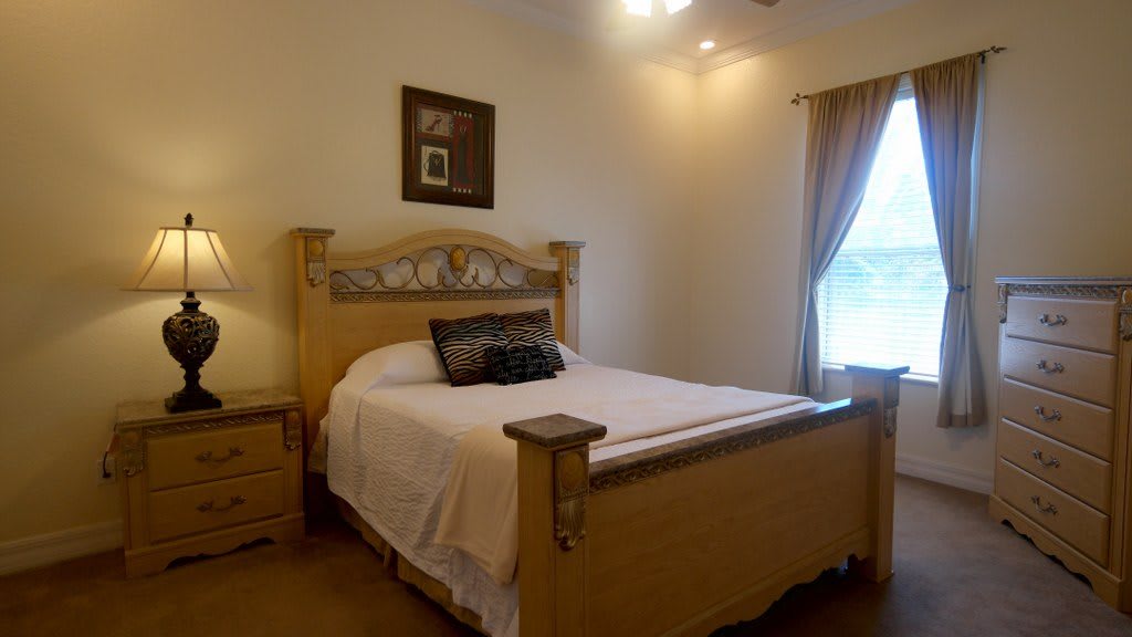 A cozy bedroom with a large bed, wooden furniture, and a window with curtains.