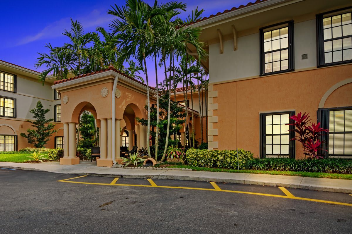 Tropical style building entrance illuminated at night, surrounded by palm trees.