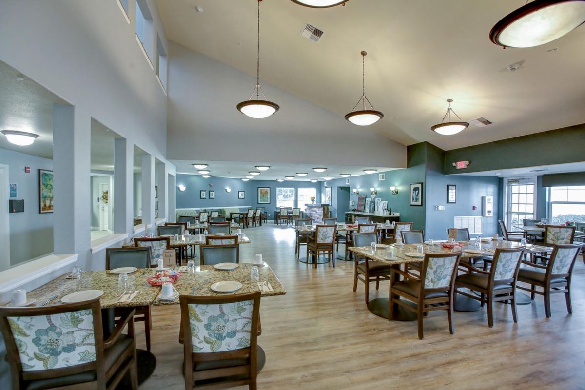 A spacious dining area with modern decor, featuring multiple tables and chairs, elegant lighting, and a welcoming atmosphere.