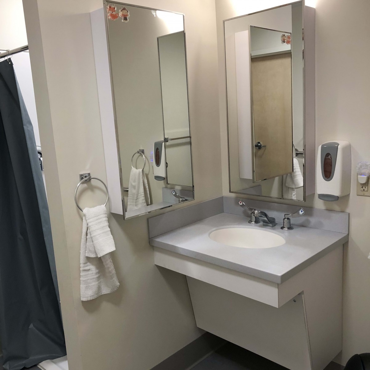 A clean bathroom with a sink, mirror, and soap dispenser.