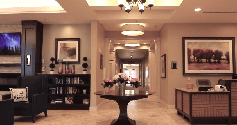 A beautifully decorated lobby with a central table, flowers, and a bookshelf in the background.